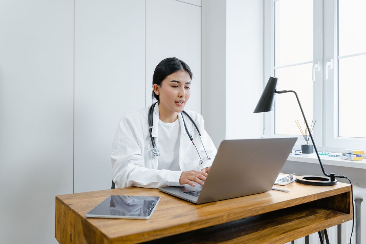 Doctora revisando datos en su portátil en la consulta